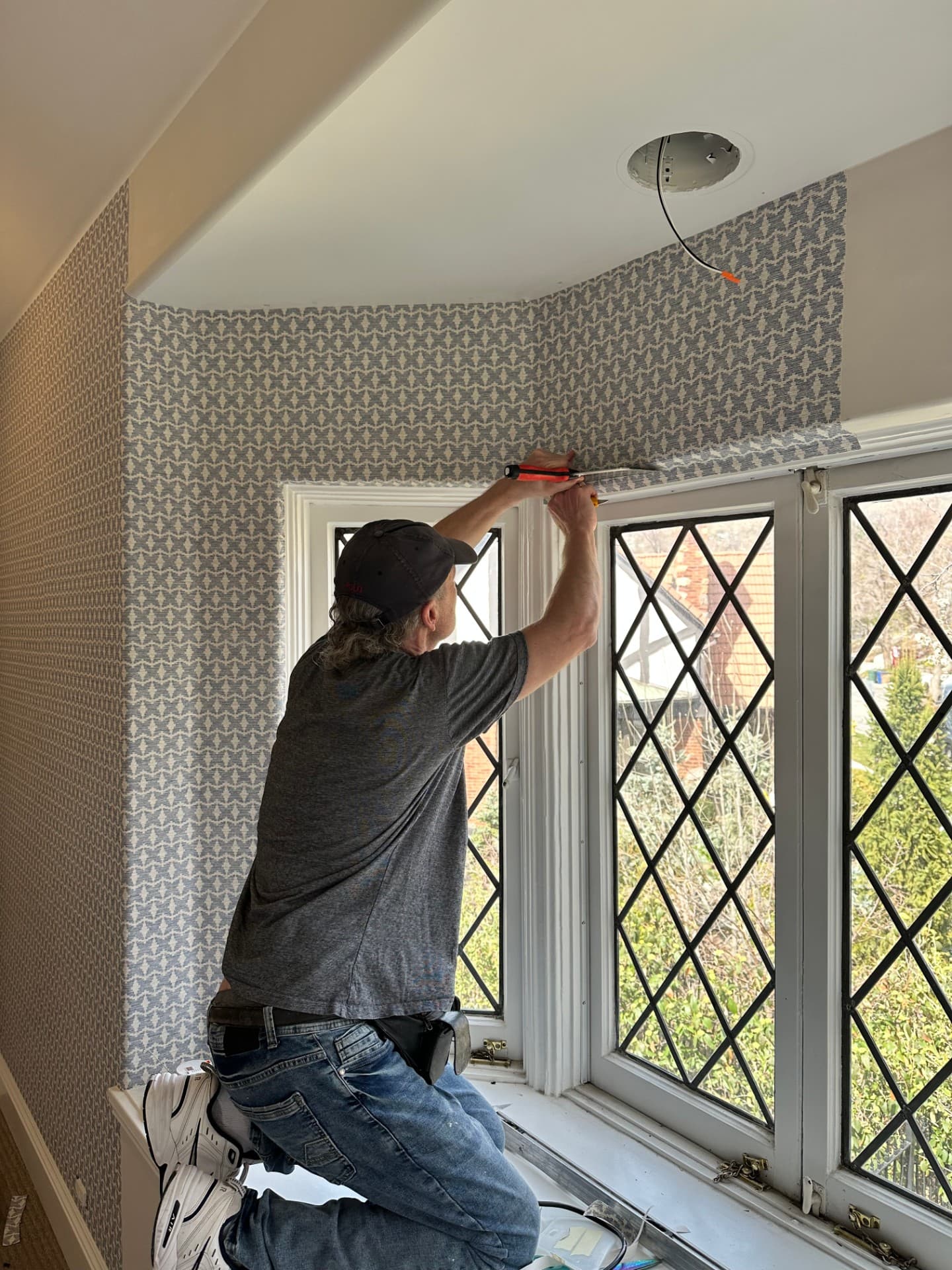 Installer mounting a ceiling light fixture in a finished room