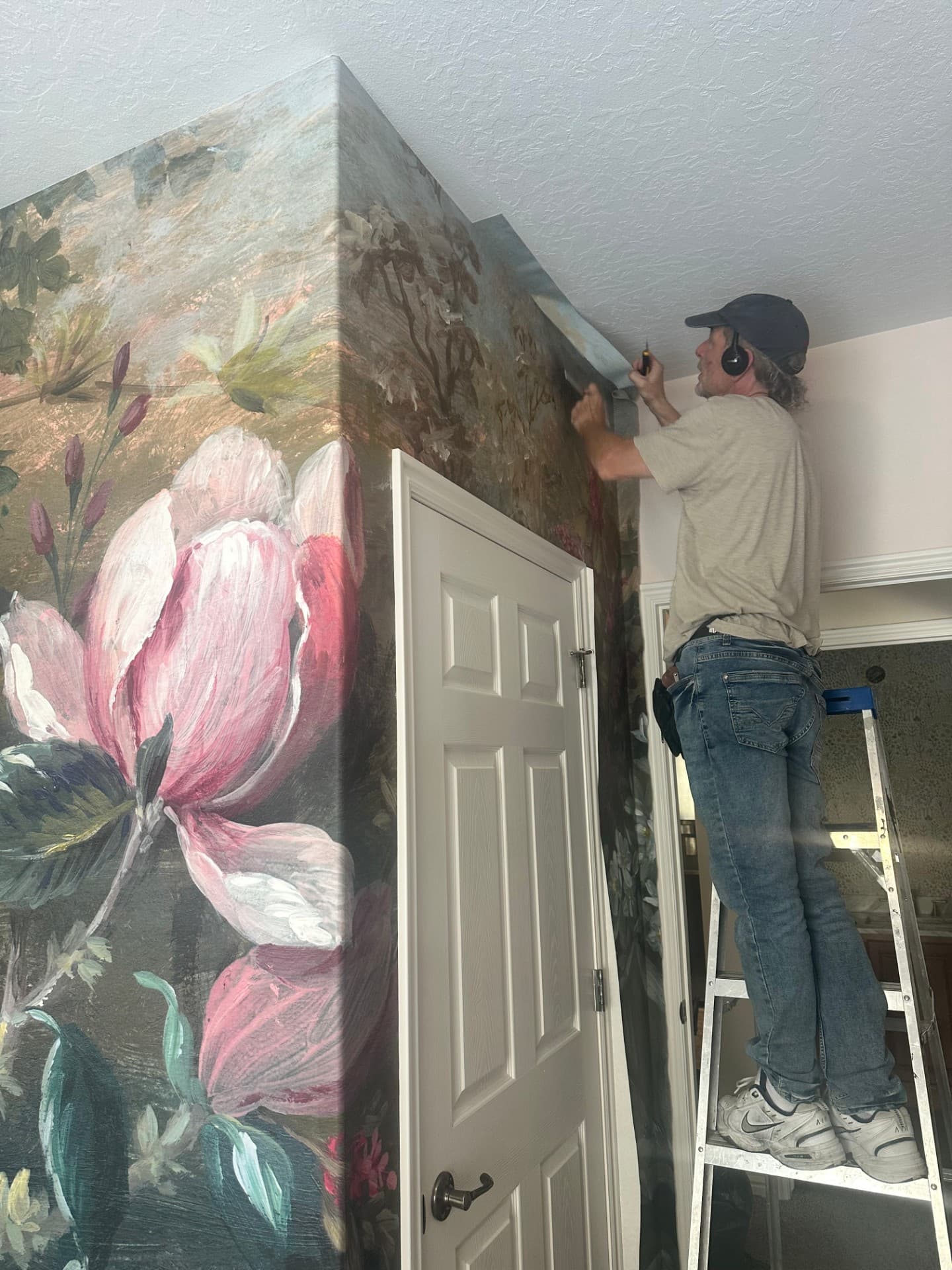 Robert installing a large-scale floral mural panel, aligning the pattern by hand