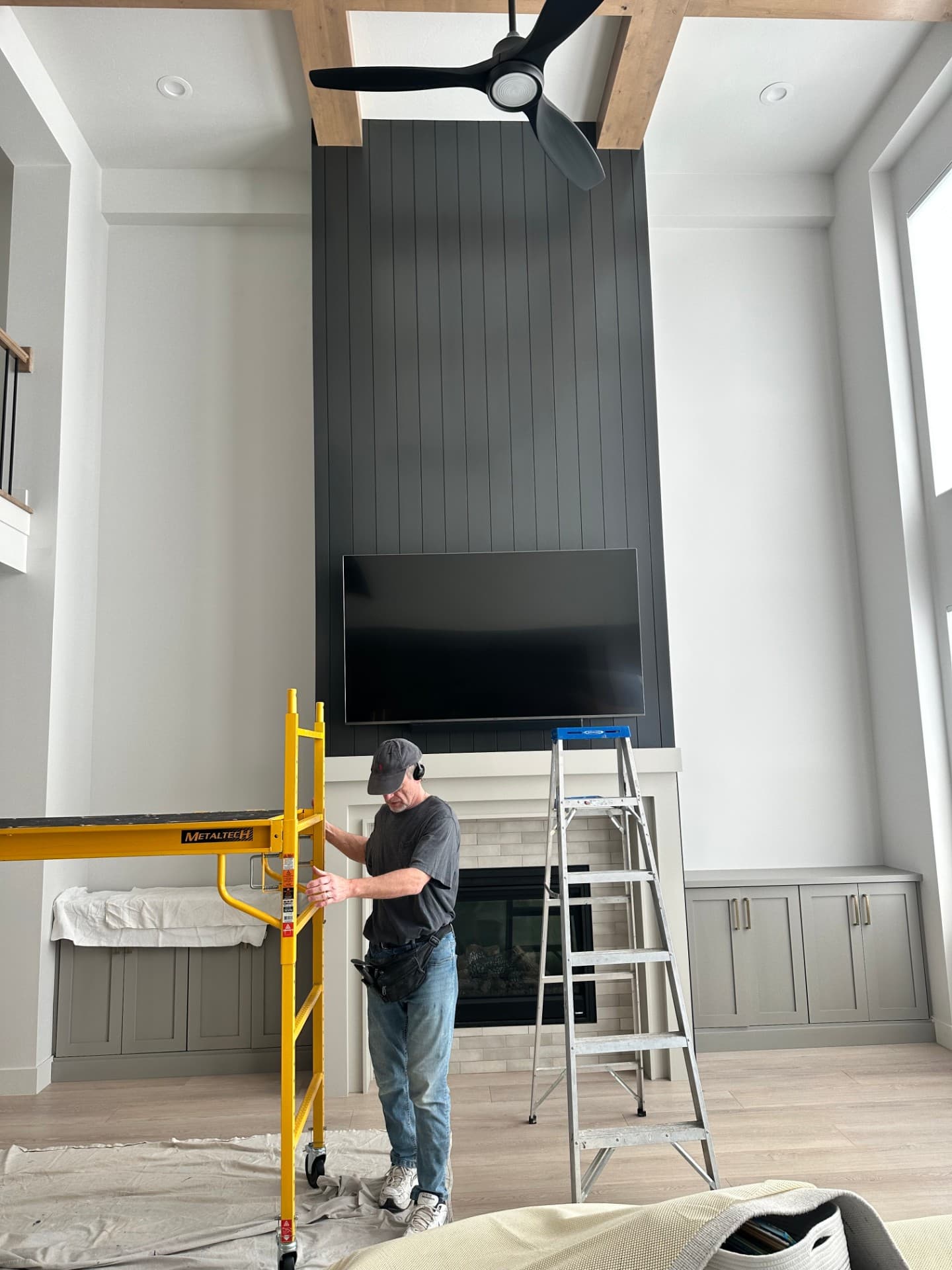 Installer mounting a TV on a freshly-papered dark accent wall