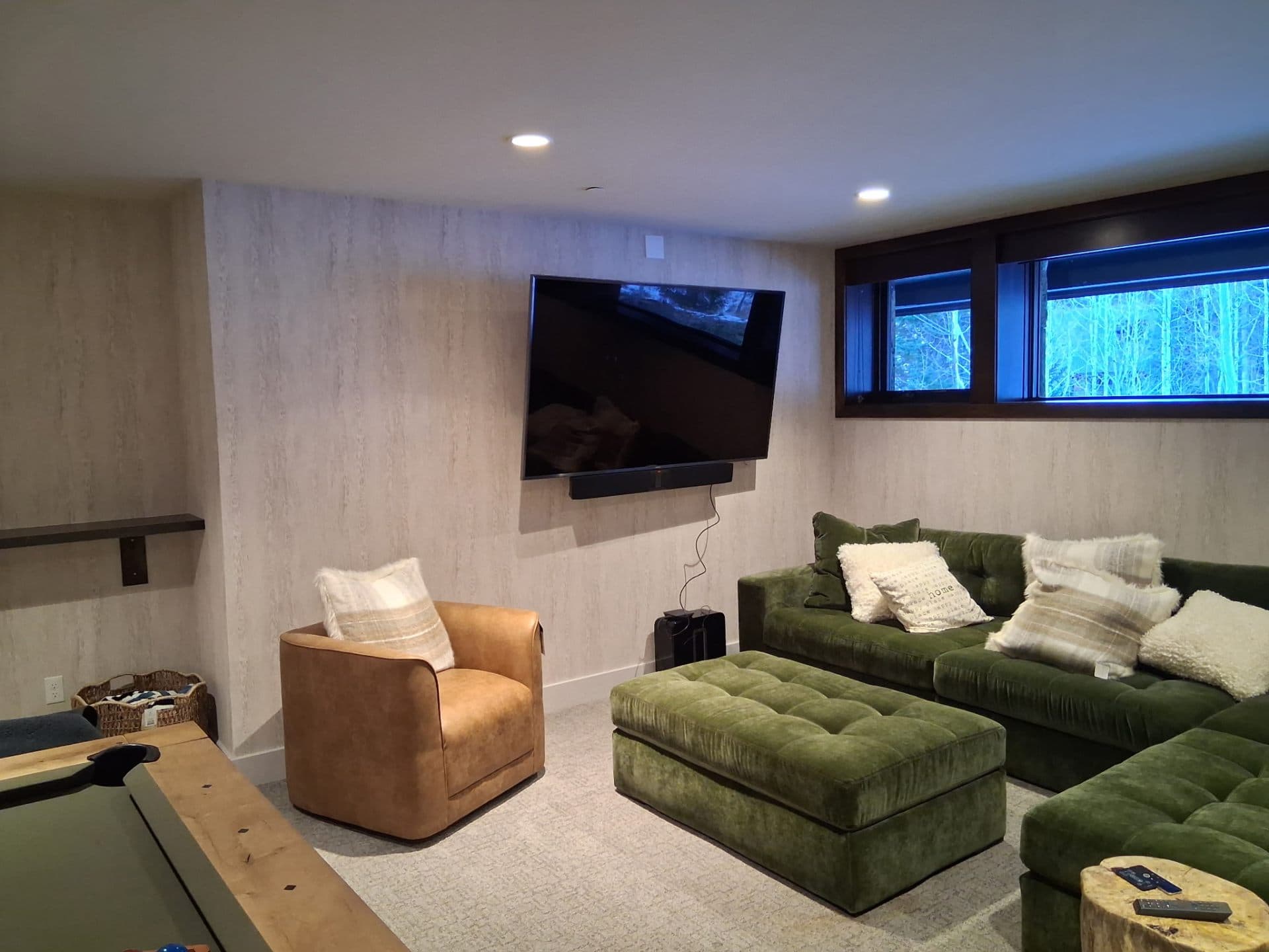 Basement media room with green seating and patterned wallpaper