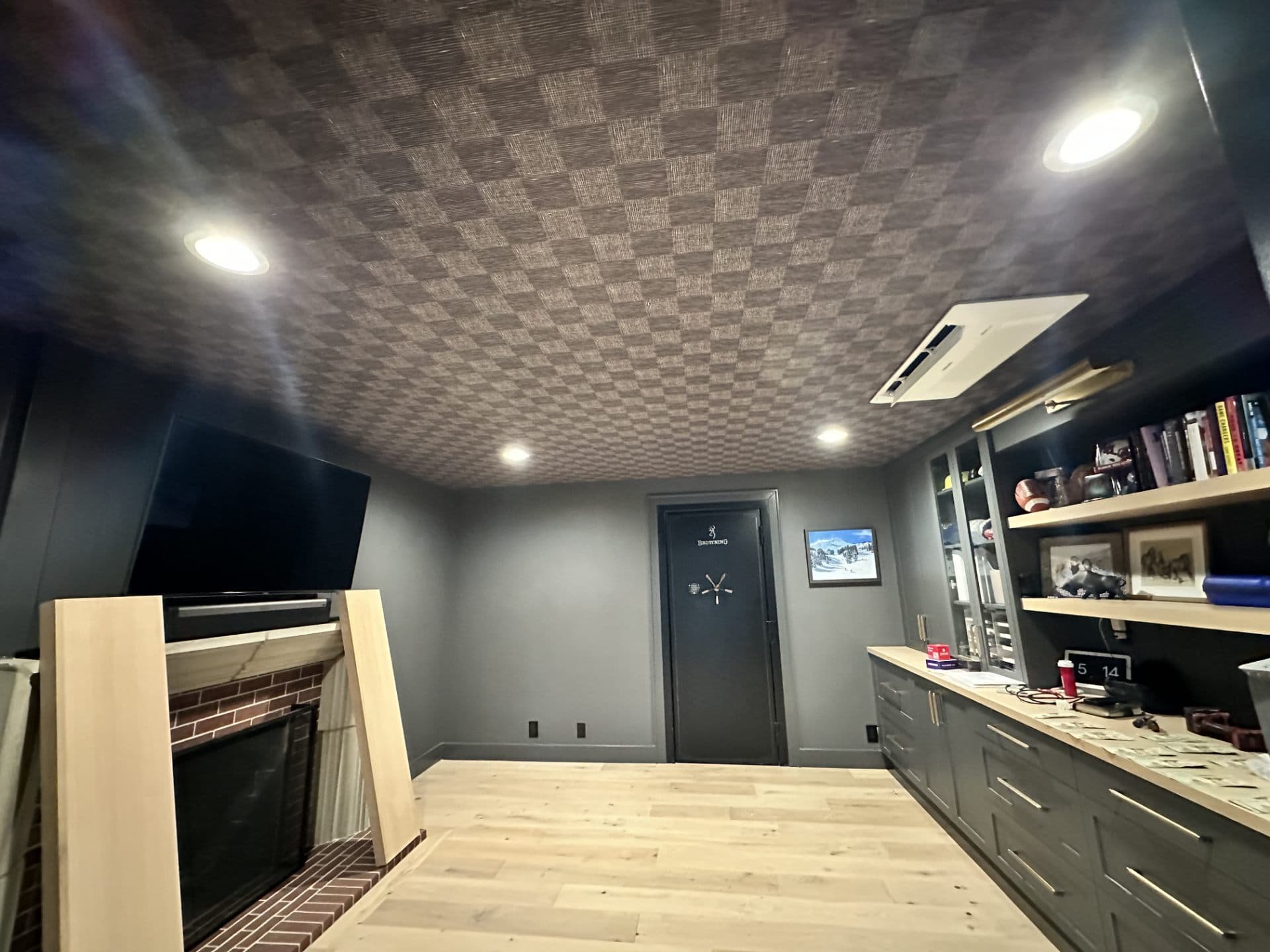 Basement office with fireplace, TV, and patterned wallpaper