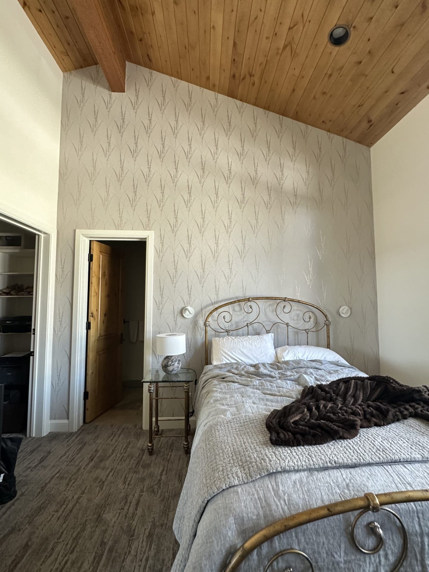 Bedroom with patterned wallpaper and a wood-paneled ceiling