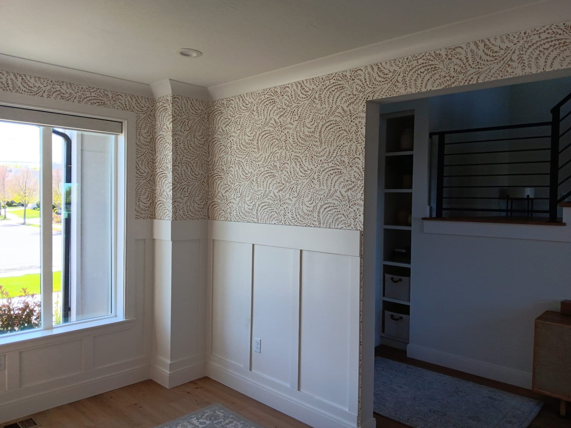 Den with patterned wallpaper above wood wainscoting
