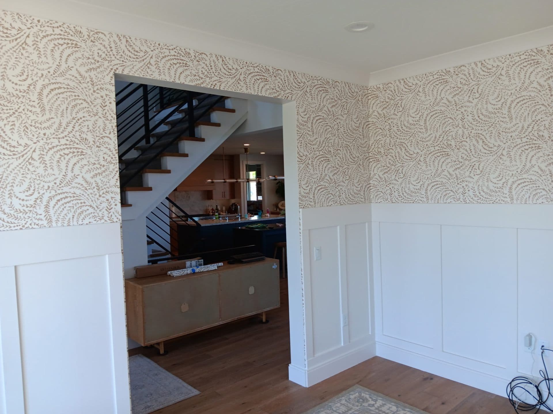 Hallway with patterned wallpaper above wainscoting