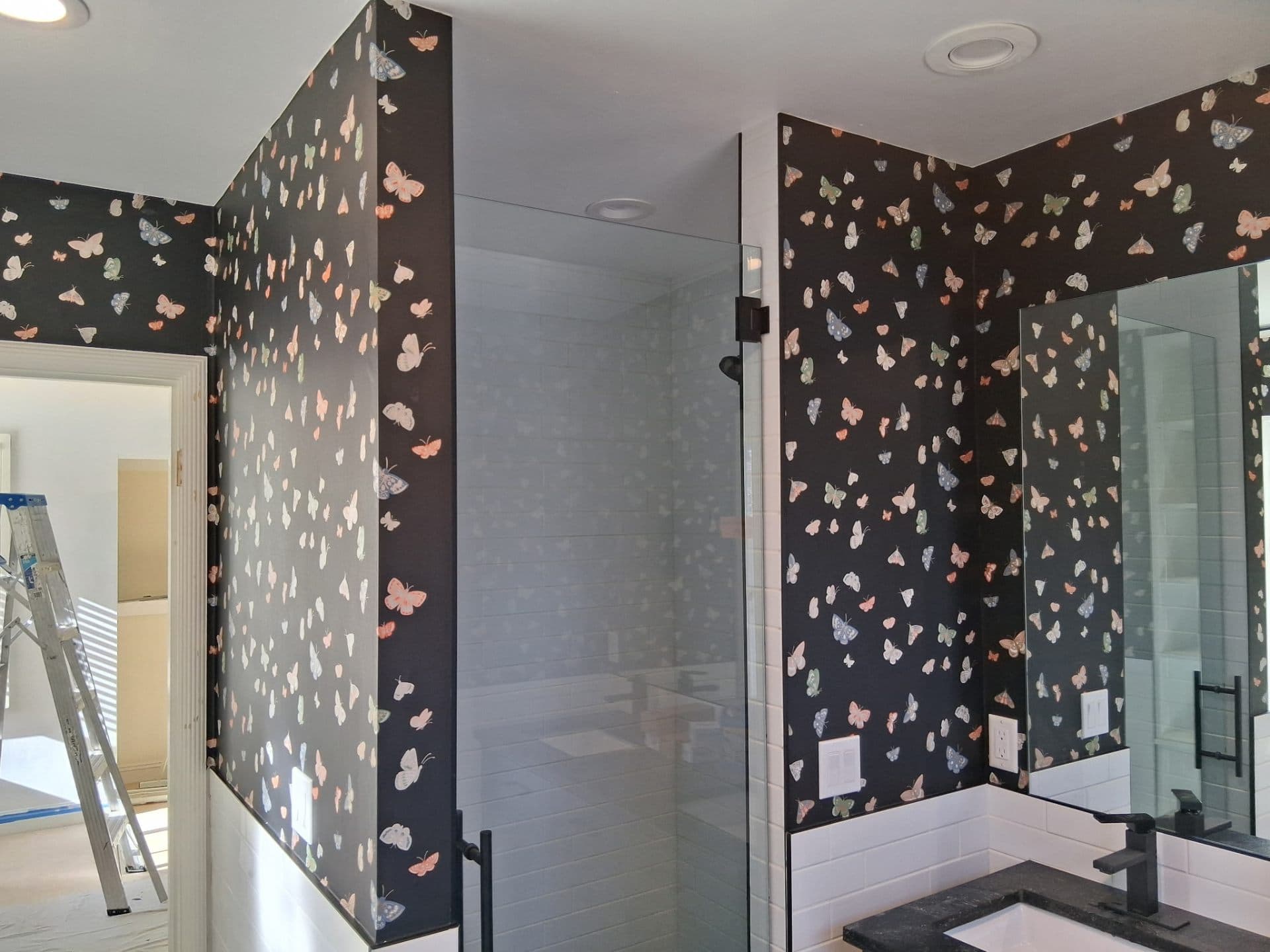 Bathroom shower wall with butterfly wallpaper cut clean around fixtures