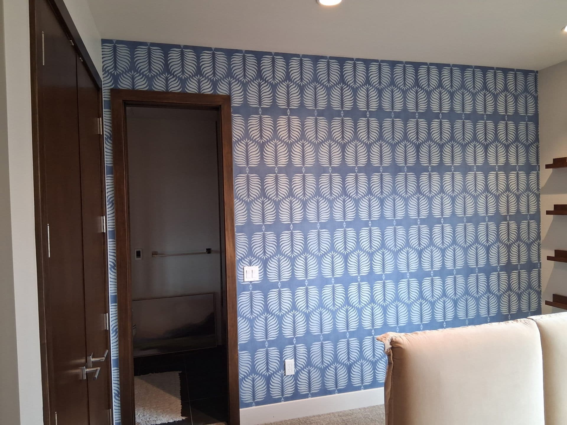Bedroom with blue botanical wallpaper behind built-in shelves