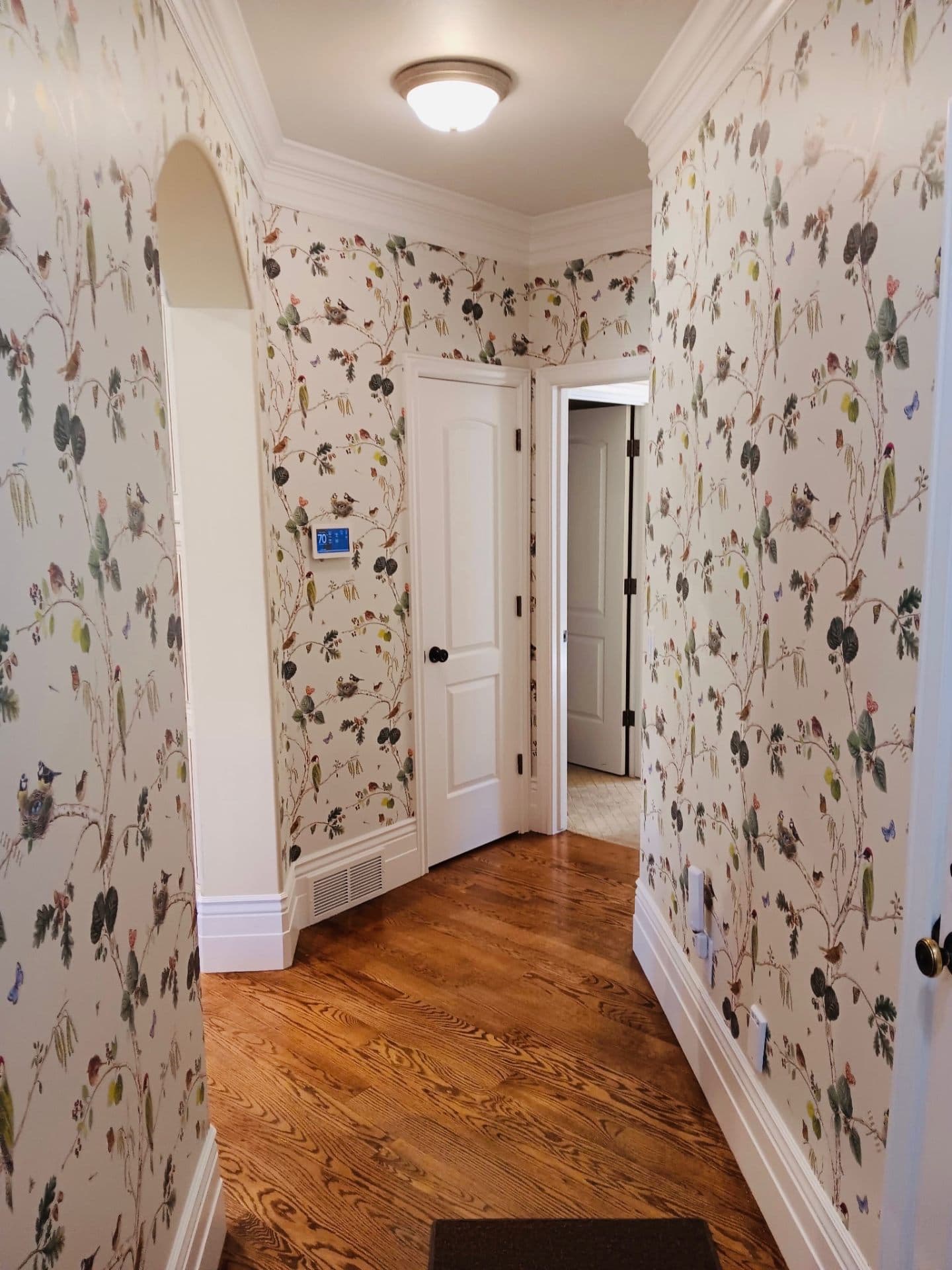 Hallway with botanical wallpaper above wood floors