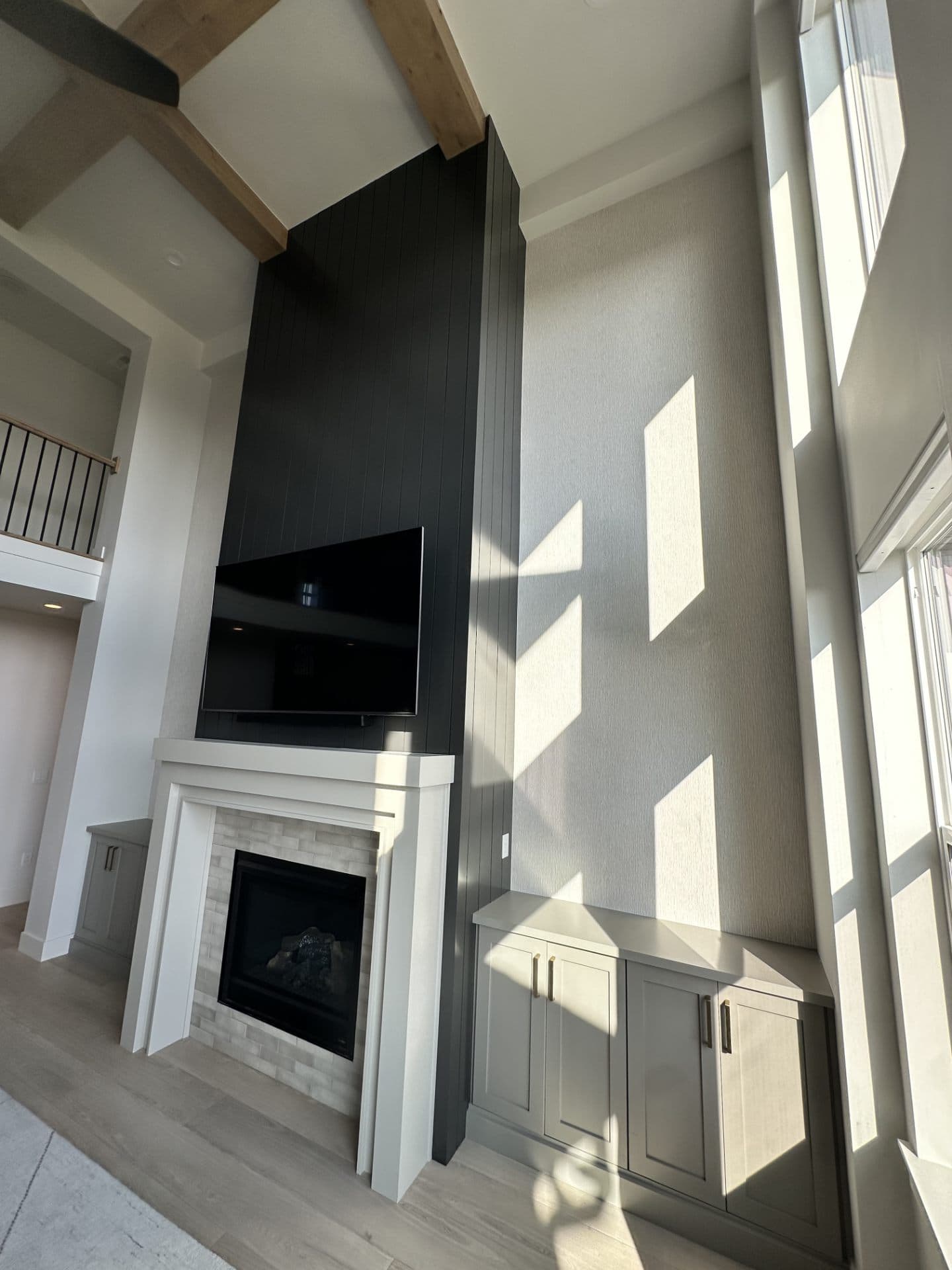 Modern living room with fireplace, television, and built-in shelving against a wallpapered wall