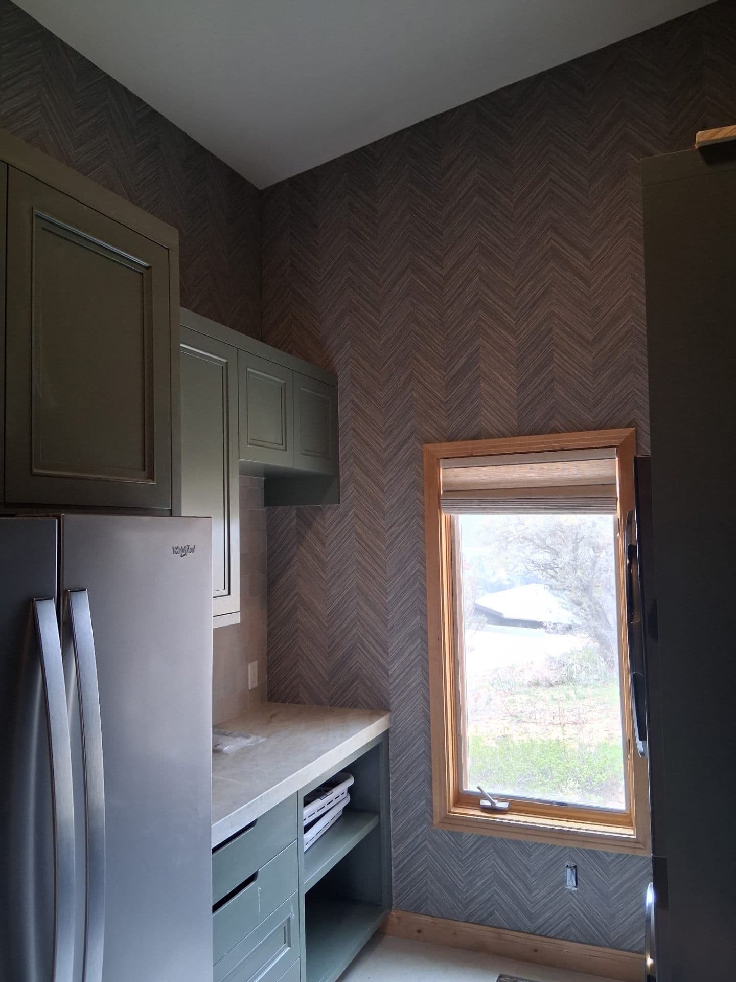 Modern kitchen with herringbone wallpaper beside a window
